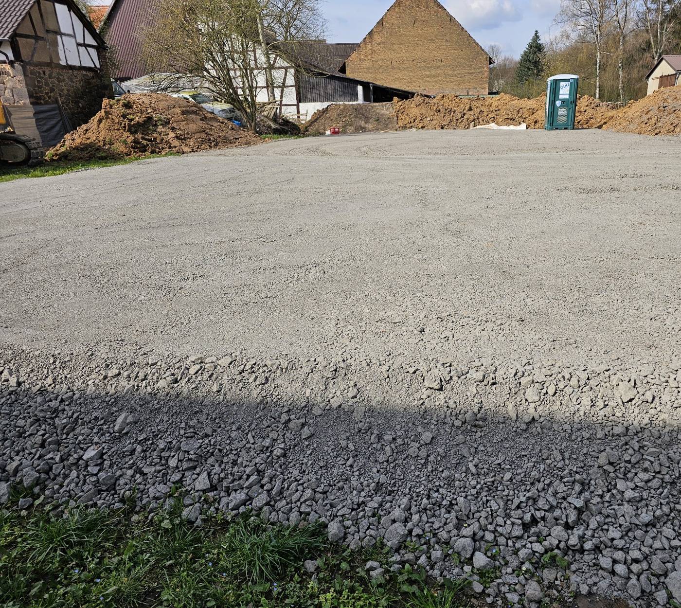 Fertig abgezogene Schotterfläche vor Fachwerkscheunen