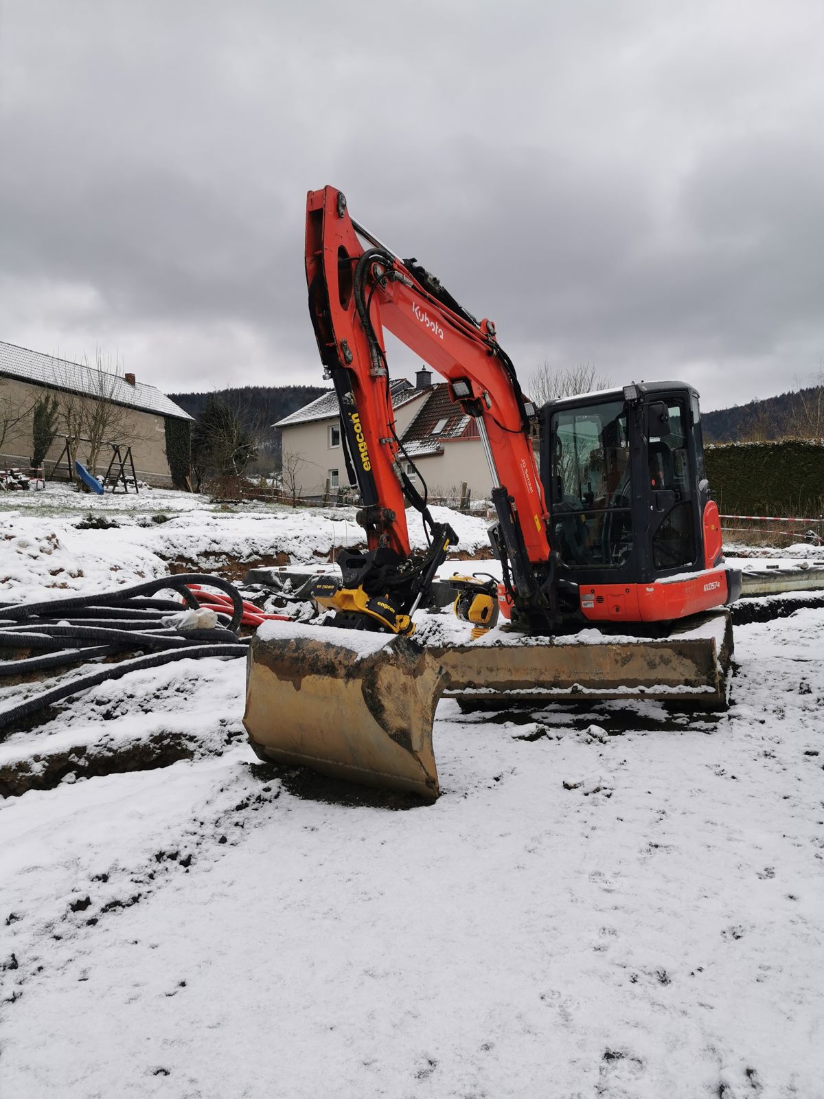 Roter Minibagger auf einer verschneiten Baustelle